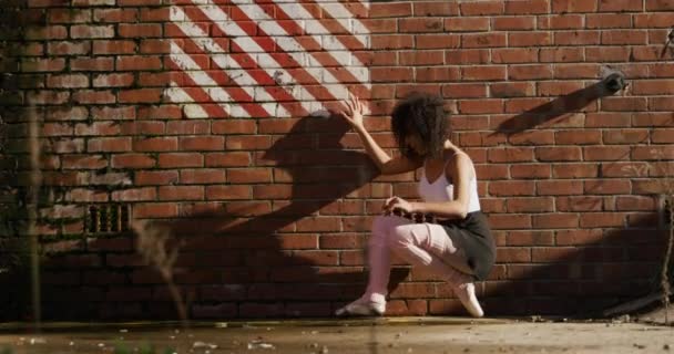 一个混血的女芭蕾舞演员在一个空荡荡的仓库外练习跳舞 靠在砖墙上 慢动作 — 图库视频影像