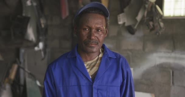 在镇上的一个工作室里 一个快乐的非洲资深男子击掌者头戴帽子 看着相机 慢动作的画像 — 图库视频影像