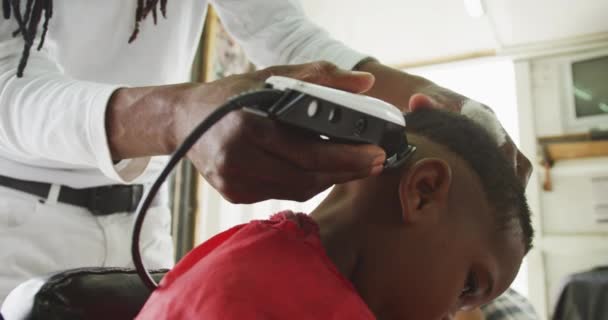 Вид Спереди Африканского Парикмахера Дредами Парикмахерской Бреющего Голову Африканского Мальчика — стоковое видео