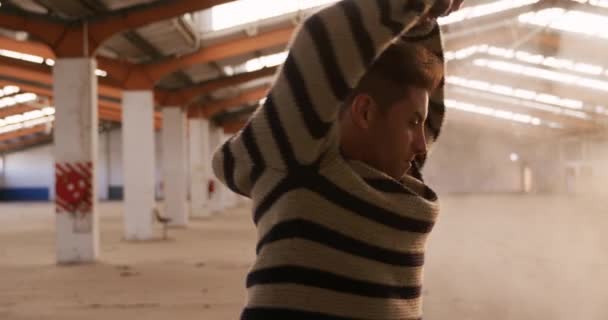 一个白人男性舞蹈演员在空荡荡的仓库里练习跳舞 手挽手在空中转身 眼前的景象非常逼真 — 图库视频影像