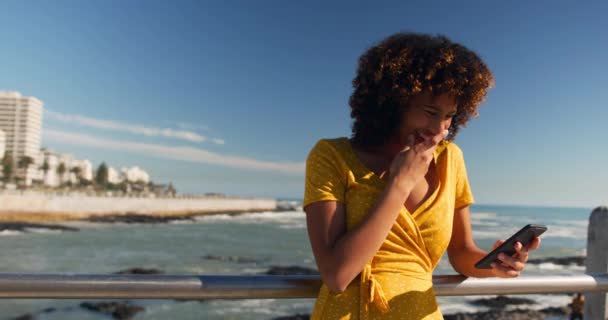 观看混合种族女性在海滨享受时光的前景色 在阳光灿烂 慢动作的日子里使用智能手机 — 图库视频影像