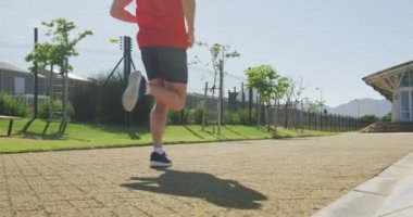 Çok ırklı bir erkek koşucu grubunun bir spor sahasında antrenman yaparken bir patikada birlikte koşarken alçak açılı dikiz görüntüsü.