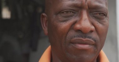 Kasabadaki bir Afrikalı adamın portresi. Turuncu gömlek giymiş ve ağır çekimde öne doğru eğilmiş. Capetown Güney Afrika 'da çekildi.