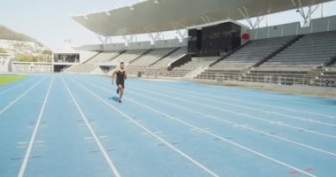 Yarış pistinde ağır çekimde koşan, bir spor stadyumunda antrenman yapan melez bir erkek sporcunun ön görüntüsü. Stadyumda Koşu ve Spor Eğitimi.