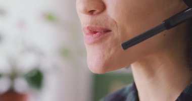 Close up of a face of happy mixed race woman working in a creative office, wearing headset, talking and smiling
