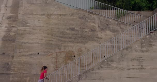 公園でのワークアウト中に階段を駆け上がるスポーツウェアを身に着けている若い白人女性のサイドビュー スローモーション — ストック動画