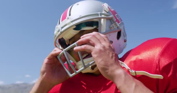 一个混血的美国足球运动员带着头盔 在运动场蓝天的映衬下慢动作 侧视近景 体育场的田径训练 — 图库视频影像
