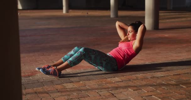 一名身穿运动服的白人年轻女子在桥下做仰卧起坐 动作缓慢的侧视图 — 图库视频影像