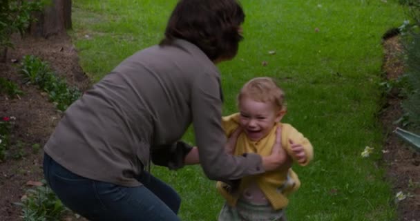一个白人妇女在花园里享受家庭时光 抱着她的孩子 转身慢慢地走来走去 眼前的景象 — 图库视频影像