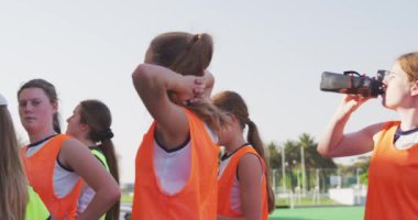 Kafkasyalı bir erkek koçun, genç bir beyaz kadın hokey takımına, maçtan önce hokey sahasının kenarındaki stadyumda, ağır çekimde,