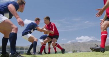 Bir grup beyaz erkek rugby oyuncusunun yan görüntüsü. Takım elbiseli, sahada oynayan bir takım, topu ele geçirmek için diğer takım, yavaş çekimde.