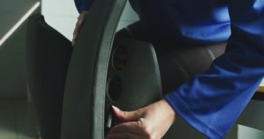 Genç, beyaz bir hokey oyuncusunun portresi soyunma odasında oturmuş çim hokeyi oynamadan önce bacak koruyucularını koruyor.