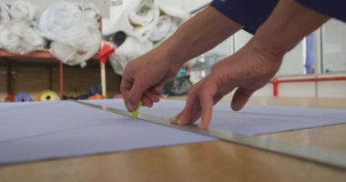 Bir fabrikadaki bir atölyede çalışan, tekerlekli sandalye yapan, tezgahta duran, metal cetvel kullanan ve ağır çekimde tebeşirle işaretleyen beyaz bir erkek işçinin ellerini yakın plan görüntüsü.