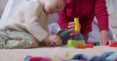 Kafkasyalı bir kadının orta kesiminde evde vakit geçiren, bebeğiyle birlikte bir çadırın yanında oturan, tahta bloklarla oynayan, ağır çekimde oynayan bir kadın.