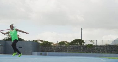Bir spor stadyumunda antrenman yapan, cirit atan, ağır çekimde beyaz bir erkek sporcunun yan görüntüsü. Stadyumda Koşu ve Spor Eğitimi.