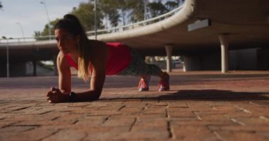 Köprünün altında egzersiz yaparken spor giysiler giyen beyaz bir kadının ön görüntüsü, ağır çekim.