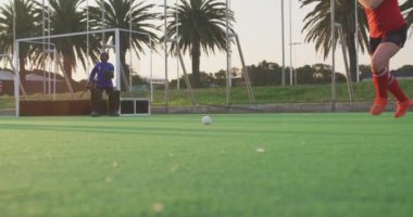 Bir spor stadyumundaki hokey maçında sahada görev yapan genç bir beyaz kadın hokey takımından bir oyuncunun düşük açılı yan görüntüsü. Gol atıyor ve kaleci Agianst 'a gol atıyor. Yavaş çekim.