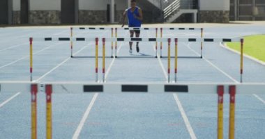 Spor stadyumunda antrenman yapan karışık ırktan bir erkek sporcunun ön görüntüsü. Koşu pistinde, ağır çekimde. Stadyumda Koşu ve Spor Eğitimi.
