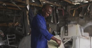 Kasabanın atölyesinde araba boyamaya hazırlanan Afrikalı bir erkek panelcinin yan görüntüsü. Capetown Güney Afrika 'da çekildi.
