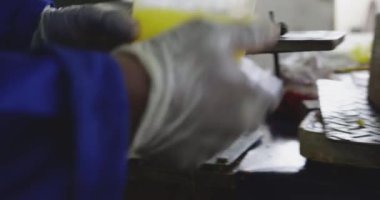 Orta kesimde eldiven ve tulum giyen bir adam, fabrikada çalışıyor kriket topları yapıyor, topların çekirdeğini karıştırıyor ve kalıba döküyor.
