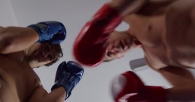 Low angle view of two Caucasian male boxers during boxing training in a boxing gym, slow motion. Tough Mixed Martial Arts Training.