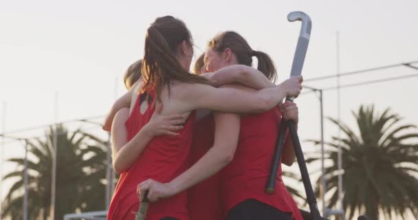 10代の白人女性ホッケーチームの選手の近くのサイドビューは スポーツスタジアムでのホッケーの試合中にピッチ上の目標を祝う抱擁 スローモーション — ストック動画