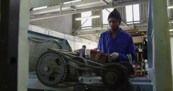 一个身穿手套和工作服的非裔美国人在一家制造板球球的工厂工作 将板球球核心的填充模子装在旋转的机器上的镜头前 — 图库视频影像