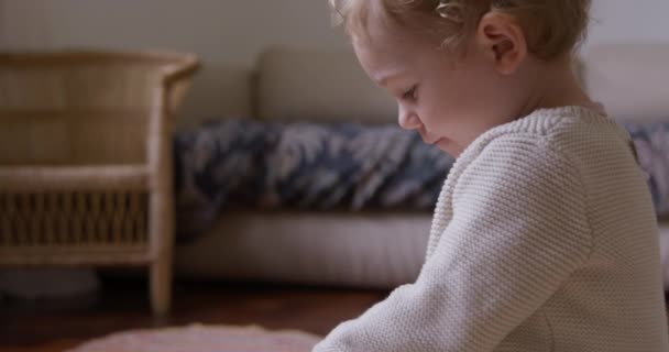 白种人幼儿在家里享受时光 坐在客厅的椅子上 集中精神往下看 慢动作的侧视图 — 图库视频影像