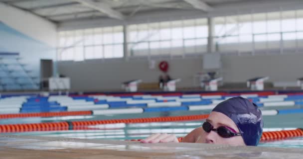白种人男子游泳运动员头像 身穿蓝色泳帽和泳镜 靠在游泳池边 动作缓慢 — 图库视频影像
