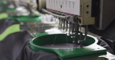 Spor kıyafetleri ve ekipman fabrikasında çabucak siyah pamuk gömlekler dikebilen otomatik dikiş makinesini kapatın.