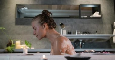 Beyaz bir kadının otelde güzel vakit geçirmesini, küvette oturup yüzünü yıkamasını, ağır çekimde