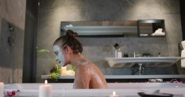 Kafkasyalı bir kadının otelde kaliteli vakit geçirmesinin yan görüntüsü, küvette maskeyle oturması, yavaş çekim.