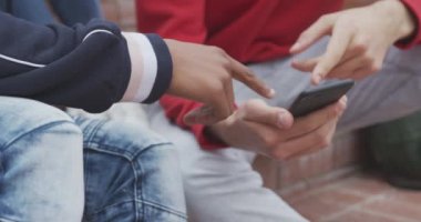 Melez bir ırkın orta kesiminde ve Kafkas ergen bir erkek öğrenci birlikte takılıyor, konuşuyor ve akıllı telefon kullanıyor, okul bahçelerinde yavaş çekimde merdivenlerde oturuyor.