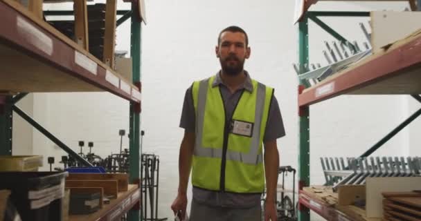 在一家制造轮椅 在货架上行走和检查零件 拿着平板电脑的工厂的仓库里 一个白人男工的前景 — 图库视频影像