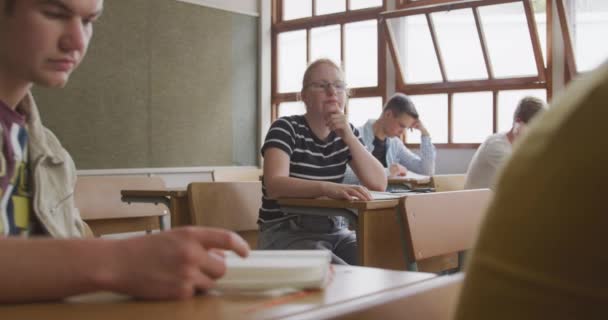 10代の男性と女性のクラスメートが彼女の周りに働く机の上に座って スローモーションで — ストック動画