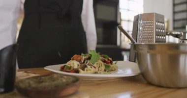 Kafkasyalı bir kadın aşçının ön tarafı ve bir restoranın mutfağında yavaş çekimde yeni hazırlanmış bir yemek tabağı.