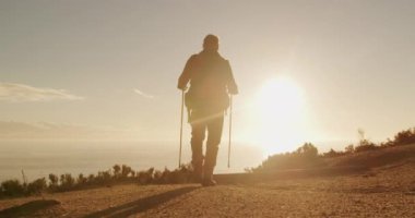 Kafkas 'lı kıdemli bir adamın doğanın tadını çıkarırken, İskandinav bastonlarıyla çayırda dikilirken, gün batımında ellerini yavaş çekimde kaldırırken.