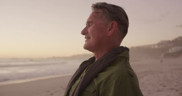 侧景近景 一位年长的白人男子在大自然中享受时光 在夕阳西下时微笑着把手放在海滩上 慢吞吞地挥动着 — 图库视频影像