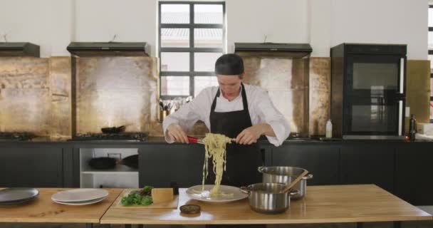 レストランのキッチンで調理教室中の白人女性シェフのフロントビュー トンとプレート上の新鮮な調理パスタを配置 スローモーションで — ストック動画