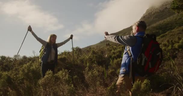 코카서스 부부가 등산중 초원에서 시간을 즐기고 남자는 노르딕걷는 막대기로 동작으로 — 비디오