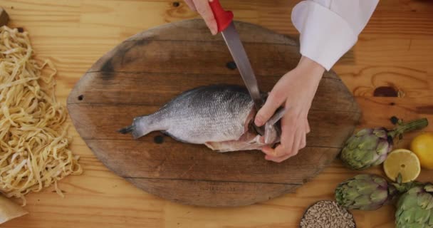 在餐馆厨房的烹饪课上 一个白人女厨师手的高角中段视图 用一把锋利的小刀在木制切菜板上切割生鱼片 准备慢动作地过滤 — 图库视频影像