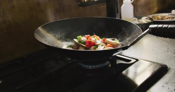 Gros plan d'une friture de légumes frais arrosant la bouche, frire dans un wok chauffé, debout sur une plaque de cuisson, au ralenti 