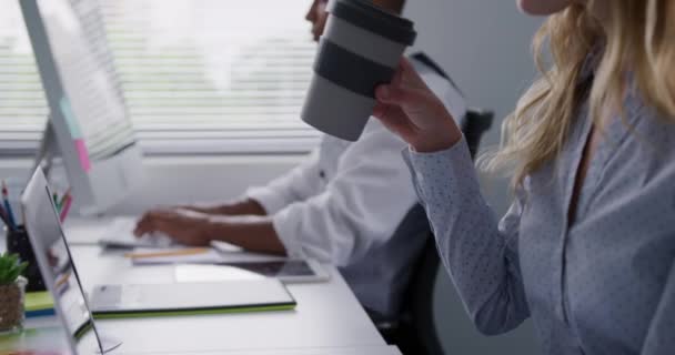 創造的なオフィスで働く白人女性と混合人種の男の側面図 コンピュータで働く女性はコーヒーを飲む スローモーション — ストック動画