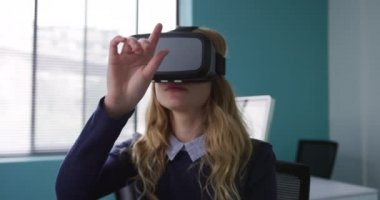 Kafkasyalı bir kadının yaratıcı bir ofiste çalıştığını, VR kulaklık taktığını, etrafa bakındığını ve sanal interaktif ekrana dokunduğunu, yavaş çekimde