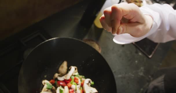 在餐馆厨房的烹饪课上 近距离观察一位白人女厨师的手 用慢动作加盐 用热锅搅拌新鲜蔬菜 — 图库视频影像