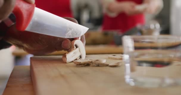 在餐馆厨房的烹饪课上 一名非洲裔美国老人用一把锋利的小刀在木制切菜板上切蘑菇 动作缓慢 — 图库视频影像