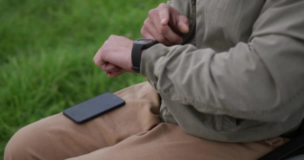 휠체어에 남성의 슬로우 모션으로 무릎에 스마트폰을 시계를 확인하는 — 비디오