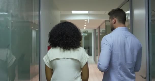 現代のオフィスで一緒に遅く働いている白人実業家と混合人種の実業家の後見人 ラップトップコンピュータを保持する男を議論廊下を歩く — ストック動画