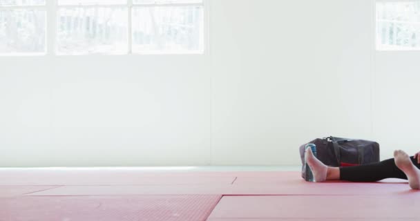 一个少年女子柔道混合赛的侧视图 在体操垫上热身 柔道训练前伸展腿 慢动作背景中的体操袋 — 图库视频影像