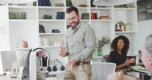 現代のオフィスで働いている白人のビジネスマンの側の見解は 彼の机のそばに立って 彼の同僚と笑顔で成功を祝う笑顔で踊り スローモーションで机で働いています — ストック動画